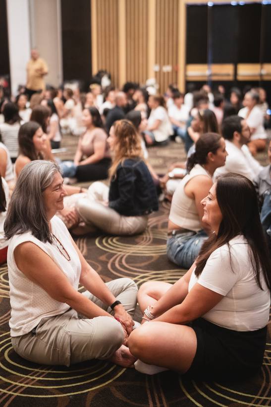 Participantes sentadas en el suelo conversan en círculo