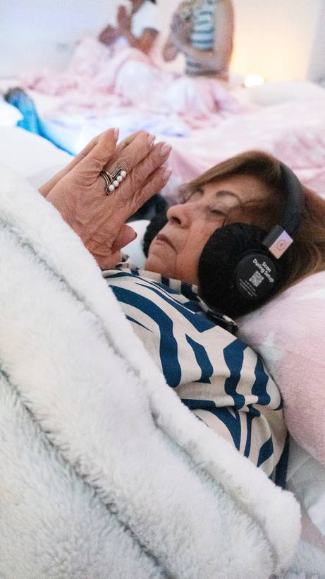 Mujer recostada con audífonos y las manos juntas