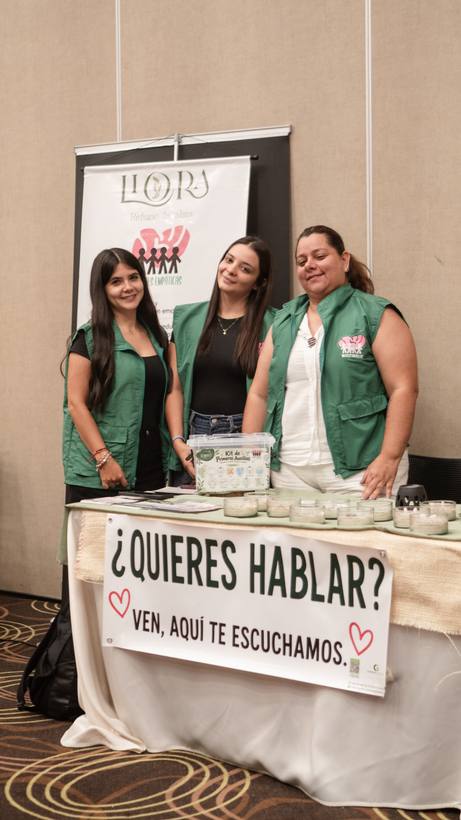 Equipo de un espacio de escucha en Vibra Fest junto a un letrero que dice «¿Quieres hablar? Ven, aquí te escuchamos»