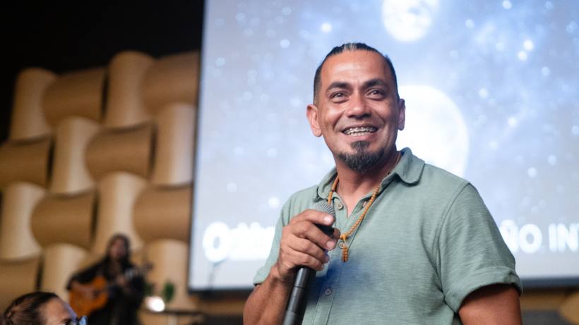 Un conferencista sonríe con el micrófono en la mano en el escenario de Vibra Fest
